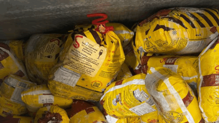 Diversos frangos congelados da marca Sadia embalados em sacos amarelos, empilhados dentro de um freezer industrial.