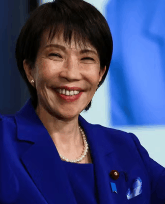 Sanae Takaichi de mãos dadas, braços levantados e sorrindo.