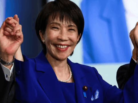 Sanae Takaichi de mãos dadas, braços levantados e sorrindo.