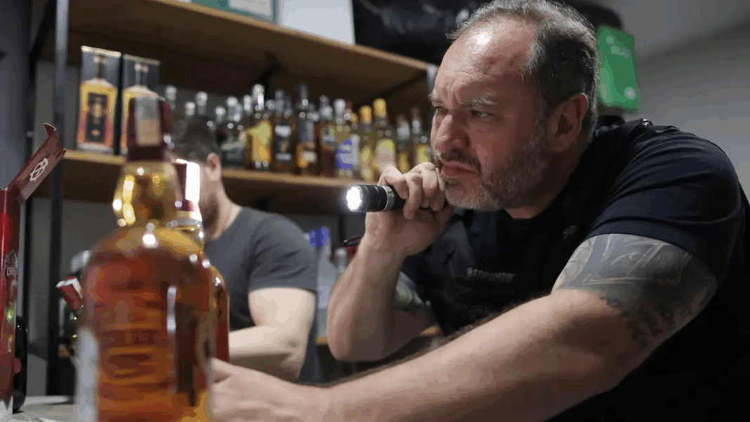 Policial aponta lanterna para uma bebida alcoólica
