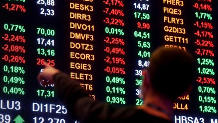 Homem aponta para números em painel da bolsa de valores