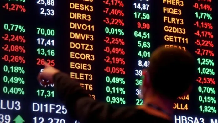 Homem aponta para números em painel da bolsa de valores