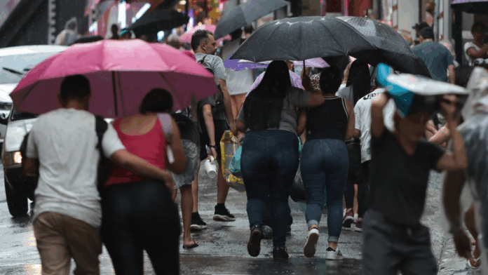Pessoas em São Paulo andando sob um guarda-chuva em dia chuvoso na capital