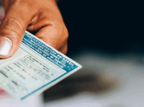 Mão de uma pessoa negra segurando uma CNH