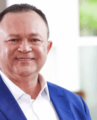 Carlos Brandão de roupa social, sorrindo e olhando para a câmera