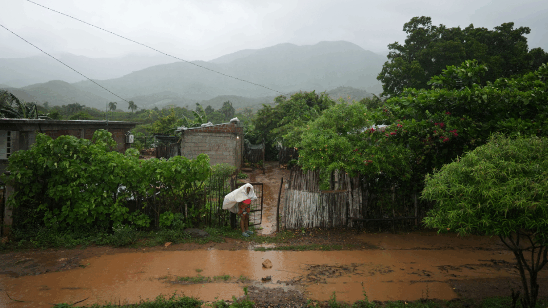 Mulher tenta se proteger do furacão em frente a uma rua alagada