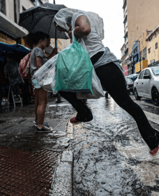 Homem pula sobre uma poça d'água ao atravessar a rua na faixa de pedestres