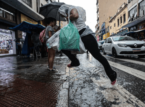 Homem pula sobre uma poça d'água ao atravessar a rua na faixa de pedestres