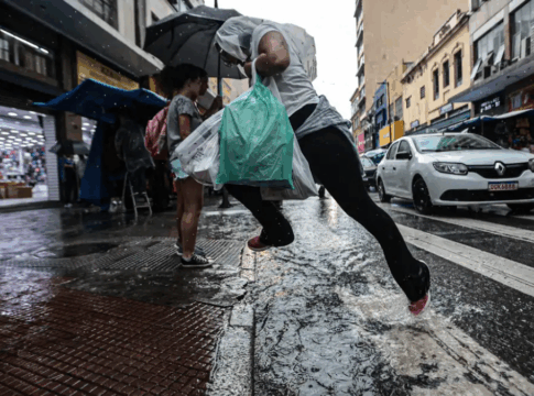 Imagem colorida de homem pulando uma poça d'água ao atravessar a rua