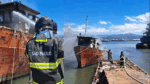 Bombeiros de São Paulo combatem incêndio em embarcação atracada em marina, usando mangueiras para resfriar a estrutura.