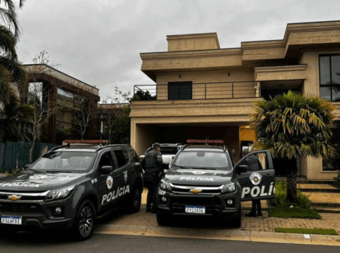 Dois carros da Polícia Militar em frente a uma casa