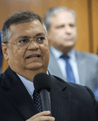 Na imagem, o ministro do Supremo Tribunal Federal, Flavio Dino, segura um microfone.