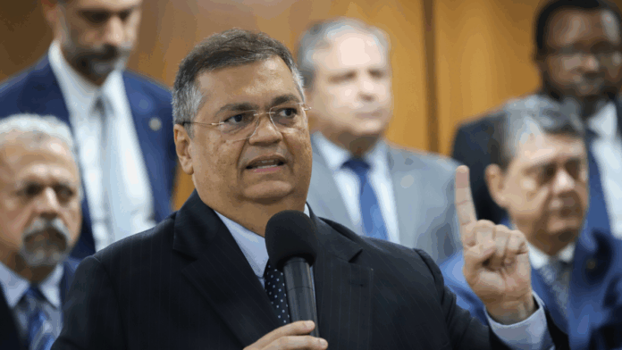 Na imagem, o ministro do Supremo Tribunal Federal, Flavio Dino, segura um microfone.