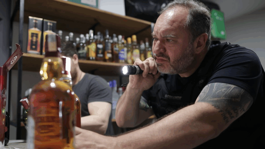 homem analisa garrafa de bebida adulterada