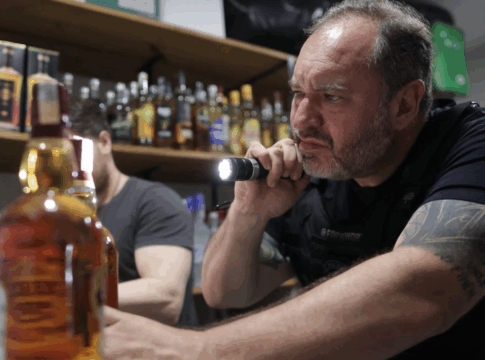 homem analisa garrafa de bebida adulterada