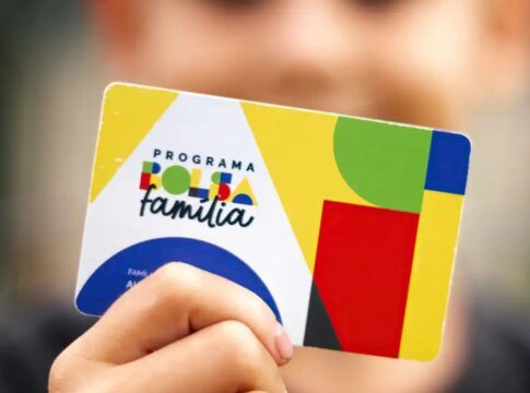 A imagem mostra uma criança segurando o cartão do Bolsa Família