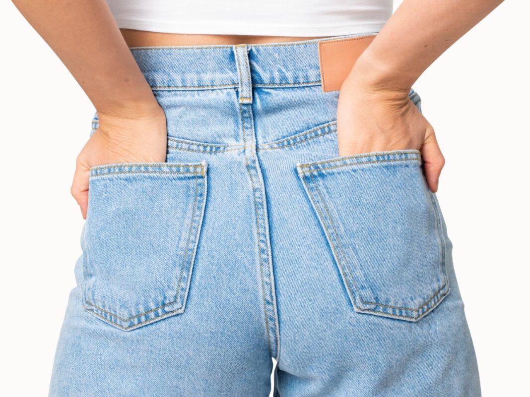Mulher de costas vestindo calça jeans com as mãos no bolso