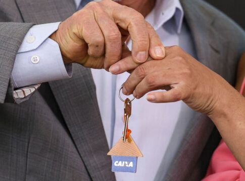 Pessoas segurando uma chave com logotipo da Caixa Econômica Federal