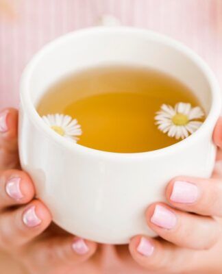 Mulher segurando xícara com chá de camomila