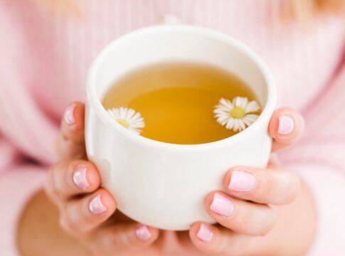 Mulher segurando xícara com chá de camomila