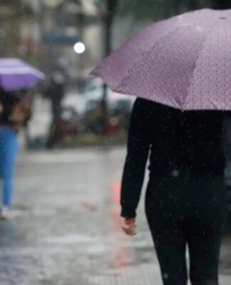 Pessoas andando na rua com guarda-chuva durante temporal