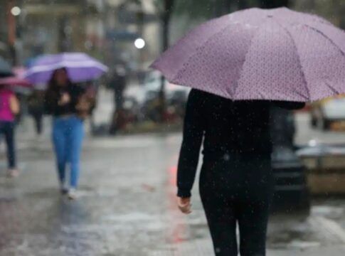 Pessoas andando na rua com guarda-chuva durante temporal