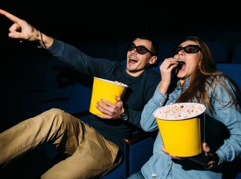 Homem e mulher comendo pipoca no cinema