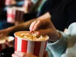 Pessoa comendo pipoca no cinema