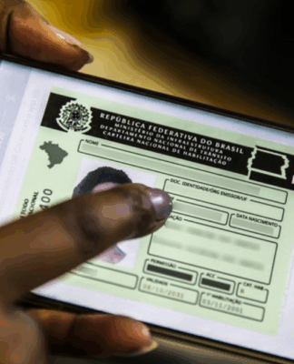 Mão segurando um celular e na tela a foto de um documento de CNH digital