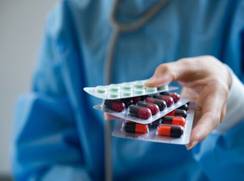 Médica segurando cartelas de comprimidos.