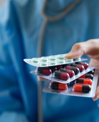 Médica segurando cartelas de comprimidos.