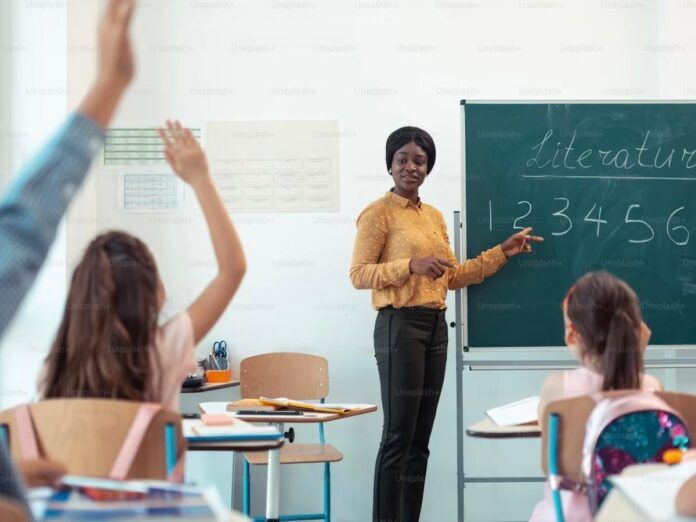 Imagem colorida de professora e alunos em sala de aula