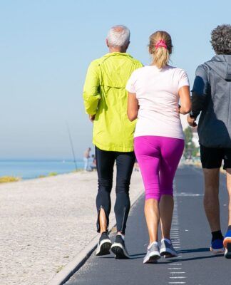 Idosos correndo em pista ao lado da praia