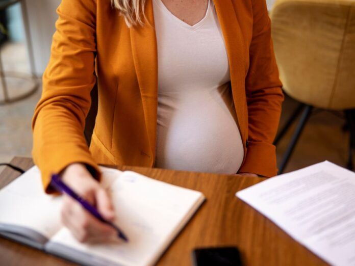 Mulher grávida assinando documentos no trabalho