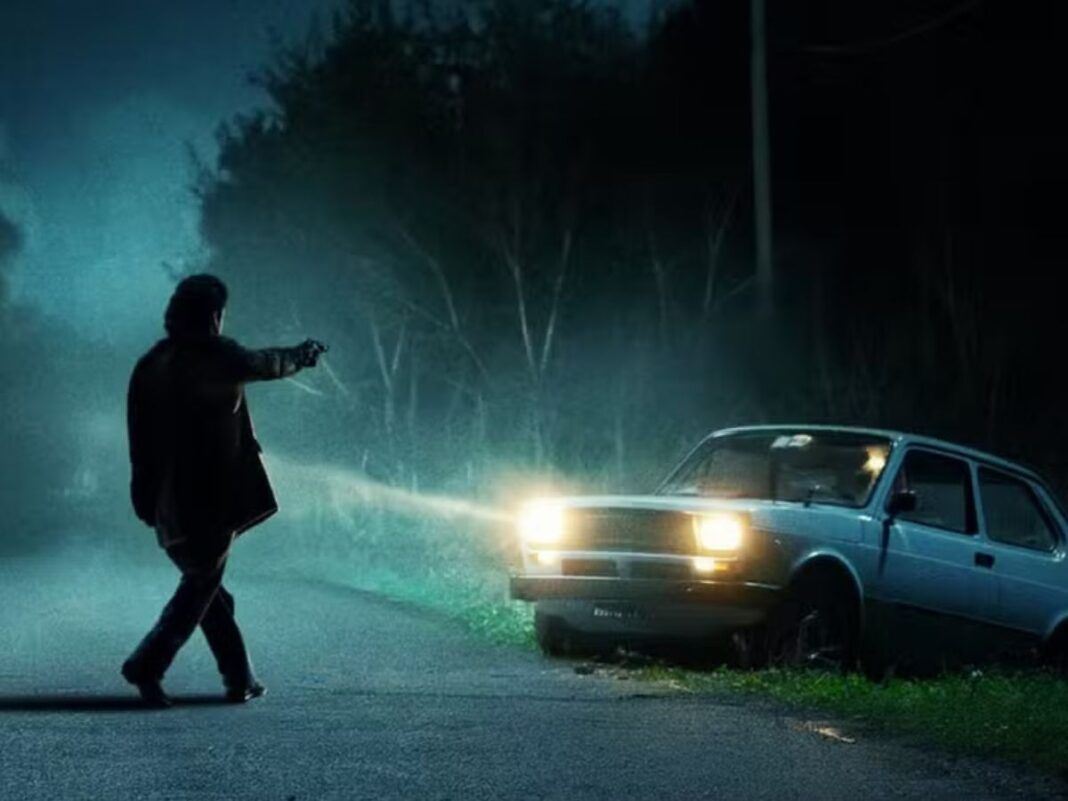 Homem apontando arma para um carro durante a noite