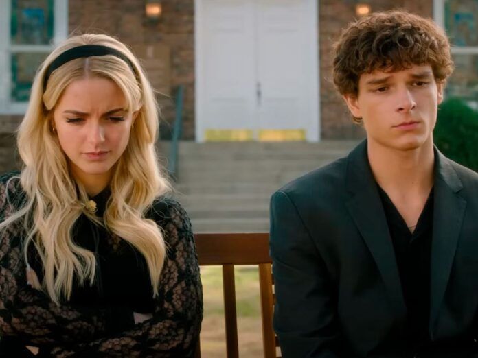 Um casal de jovens estão sentados lado a lado. A garota é branca e loira. O garoto é branco e moreno.