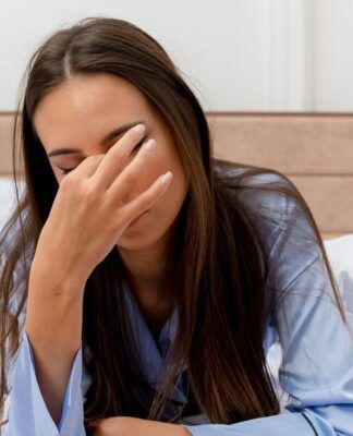 Mulher com a mão nos olhos ao acordar