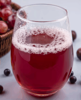 Copo de suco de uva, com várias uvas roxas no fundo