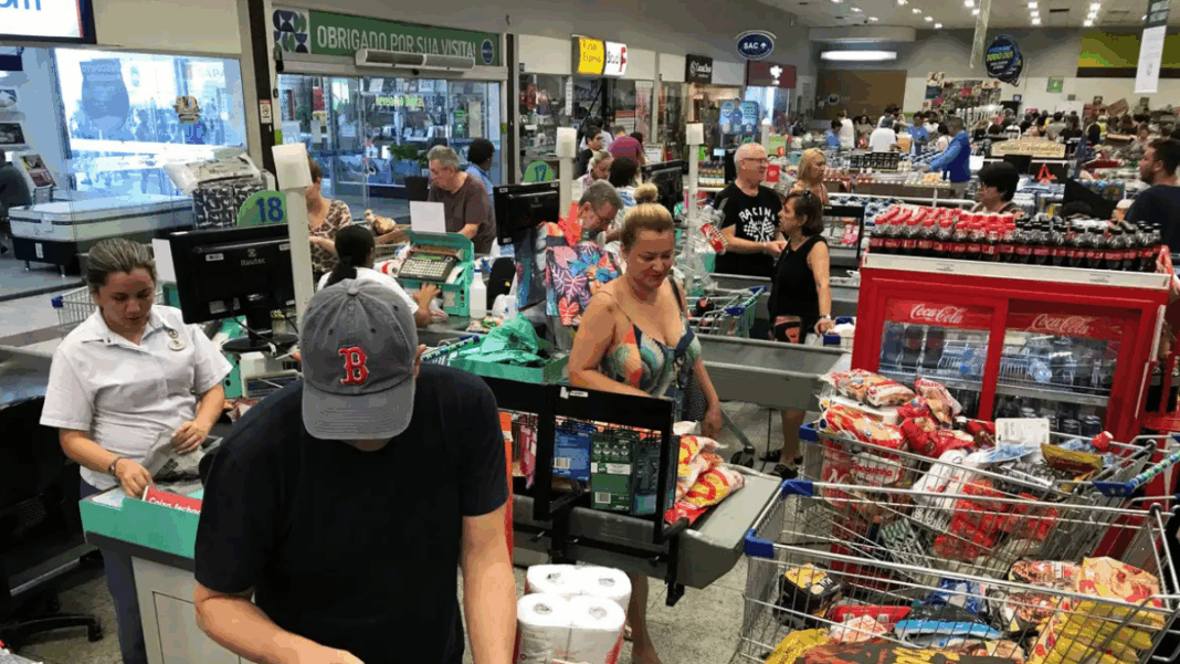 Pessoas em fila de supermercado, com compras.