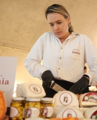 Mulher corta queijo diante de diversas peças