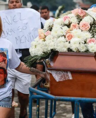 Mulher lidera cortejo fúnebre ao lado do caixão do marido