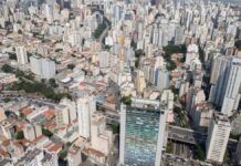 Do alto aparecem casas e diversos prédios da zona central de São Paulo