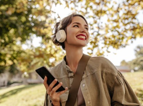 Garota com fone feliz andando em um parque.