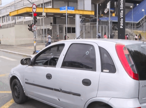 imagem de veículo com marcas de tiros parado no meio de uma avenida