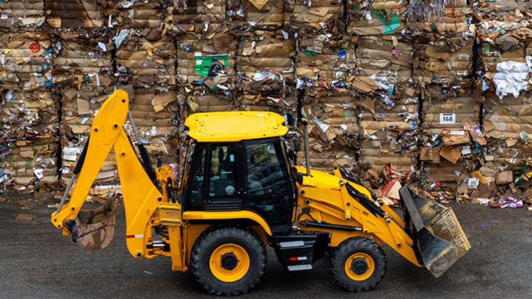 Trator carrega pilhas de lixo reciclado