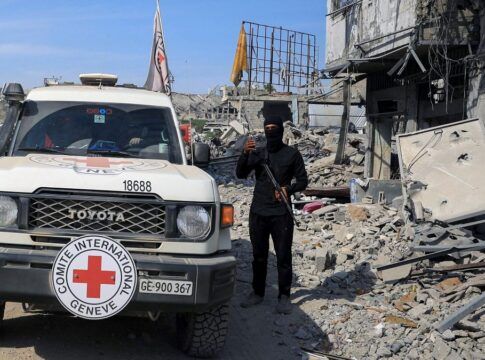 Carro da Cruz Vermelha é acompanhada por guarda do Hamas em meio aos escombros