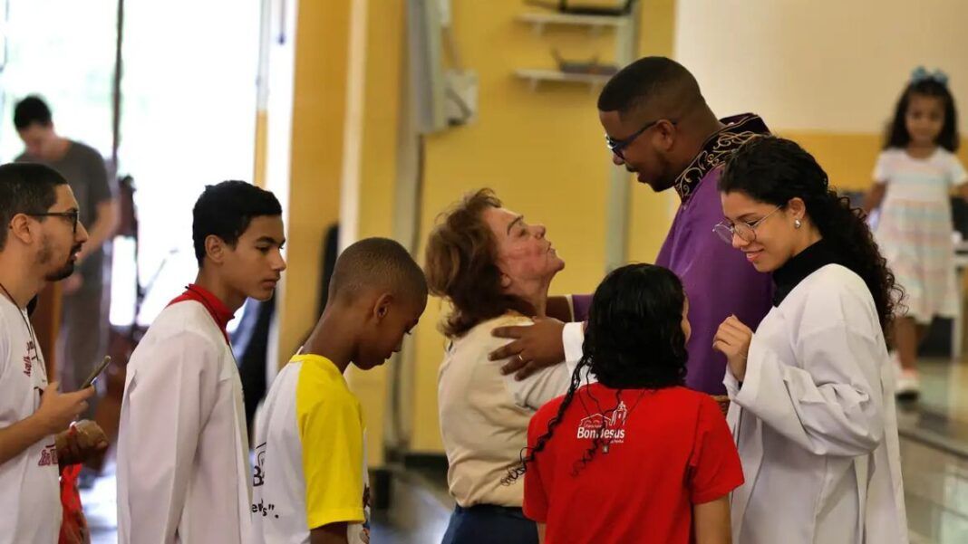 Fiéis conversam com o padre durante missa na Paróquia Bom Jesus da Penha