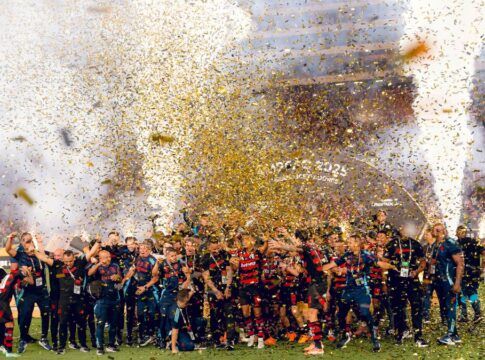 Jogadores do Flamengo festejam o tetracampeonato da Libertadores em meio a chuva de papel picado no gramado.