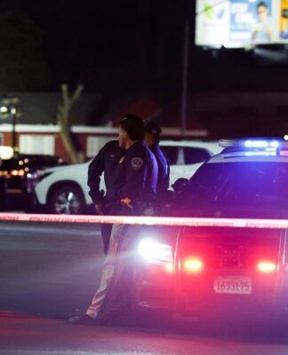 Policiais estão ao lado de um carro policial no local do crime, na cidade californiana