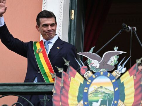 Rodrigo Paz com faixa presidencial na sacada, acenando para população boliviana